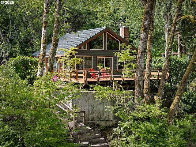 25050 Wilson River Hwy, Tillamook, OR 97141 - back of property featuring a chimney, a deck, metal roof, a forest view, and a standing seam roof