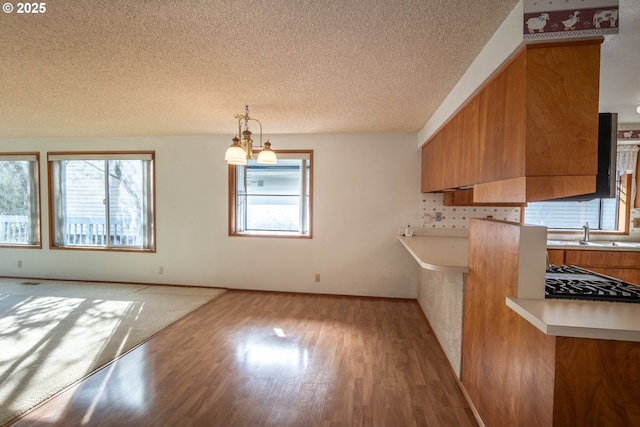 kitchen featuring light countertops, a healthy amount of sunlight, brown cabinets, and a sink