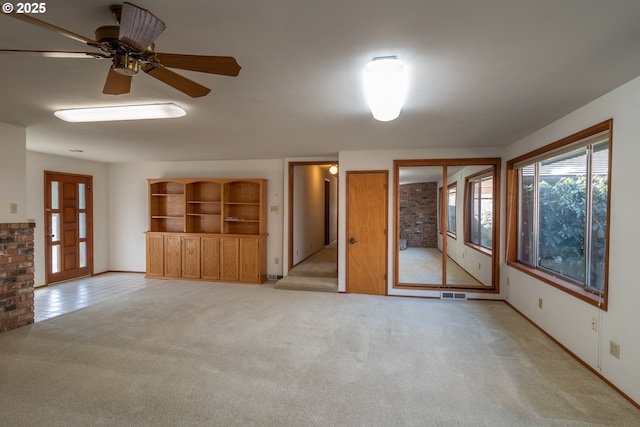 unfurnished living room with a ceiling fan, light carpet, and visible vents