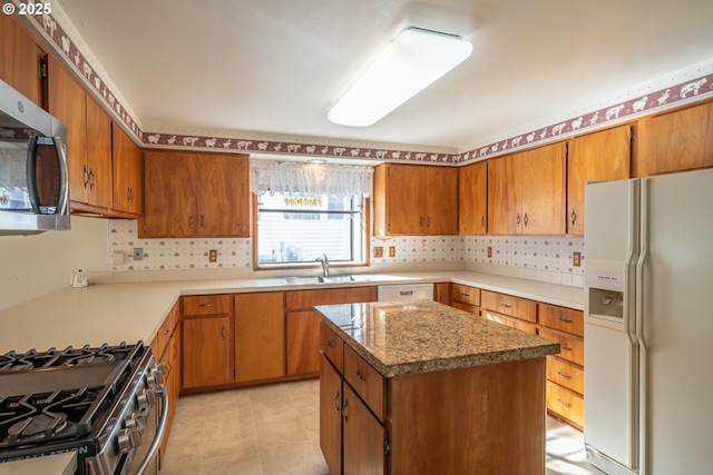 kitchen with tasteful backsplash, appliances with stainless steel finishes, brown cabinetry, and a sink