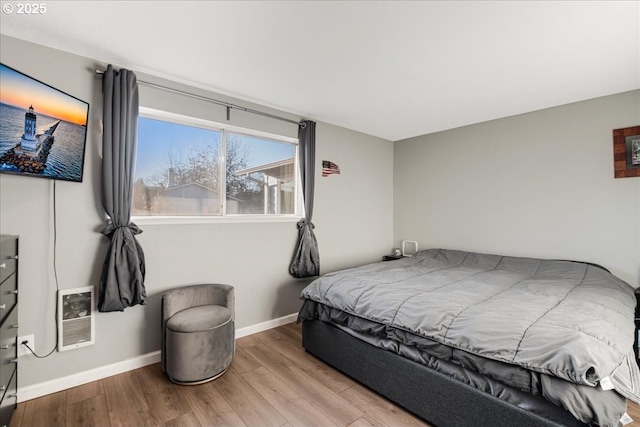 bedroom featuring heating unit and light hardwood / wood-style floors