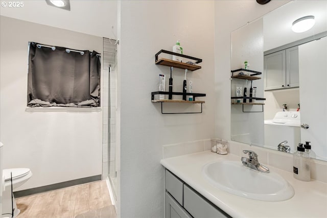 bathroom featuring hardwood / wood-style flooring, vanity, toilet, and washer / dryer