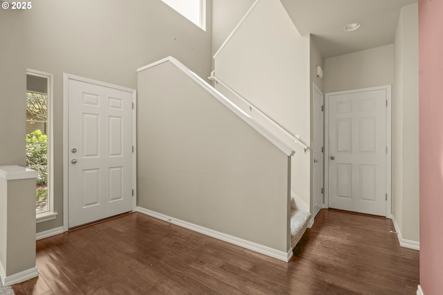 entryway with stairway, wood finished floors, baseboards, and a high ceiling