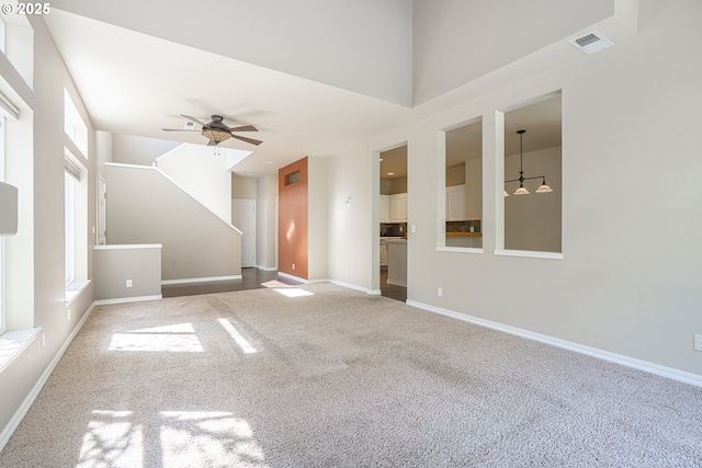 unfurnished living room featuring carpet, a ceiling fan, and plenty of natural light
