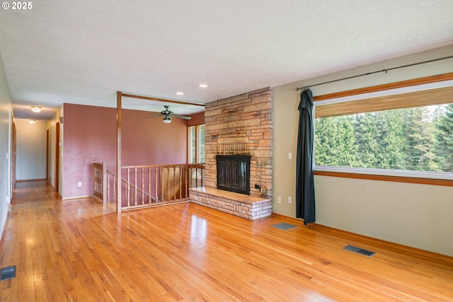 112 Paine Rd, Castle Rock, WA 98611 - unfurnished living room with a textured ceiling, wood finished floors, a ceiling fan, a stone fireplace, and recessed lighting
