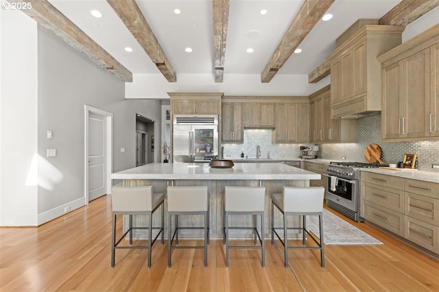 2193 NE 3rd Ave, Camas, WA 98607 - kitchen with premium appliances, beamed ceiling, a breakfast bar, decorative backsplash, and light wood-type flooring