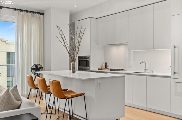 1150 NW Quimby St Unit 610, Portland, OR 97209 - kitchen featuring a kitchen island, a kitchen bar, modern cabinets, white cabinetry, and appliances with stainless steel finishes