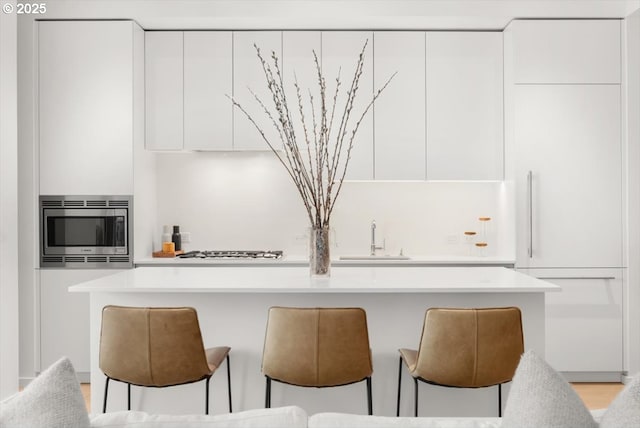 1150 NW Quimby St Unit 610, Portland, OR 97209 - kitchen featuring stainless steel microwave, modern cabinets, white cabinetry, and a breakfast bar area