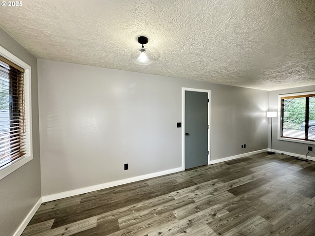 unfurnished room featuring dark wood-style floors, a textured ceiling, and baseboards