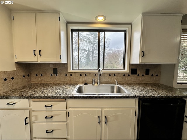 kitchen with a sink, white cabinetry, black dishwasher, backsplash, and dark countertops