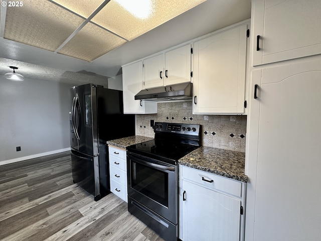 kitchen featuring under cabinet range hood, electric range, wood finished floors, white cabinets, and dark stone countertops