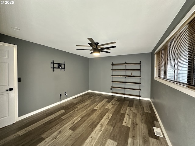 empty room featuring visible vents, dark wood finished floors, baseboards, and ceiling fan