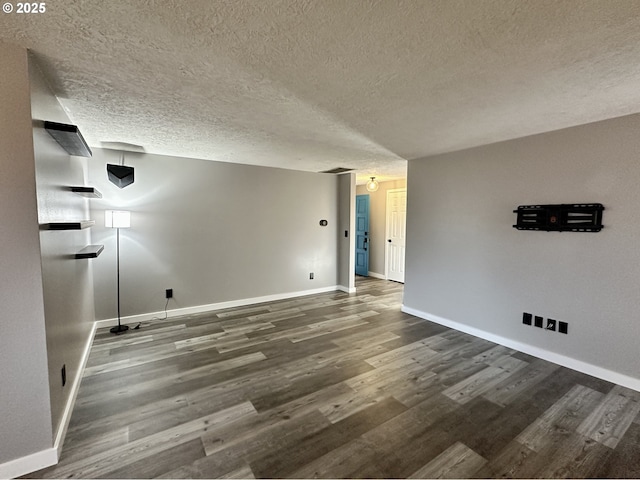 empty room featuring a textured ceiling, baseboards, and dark wood-type flooring