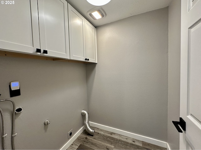 laundry room with cabinet space, baseboards, visible vents, and dark wood finished floors