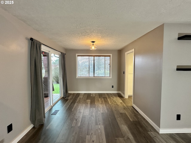 unfurnished dining area featuring dark wood-type flooring, a textured ceiling, and baseboards