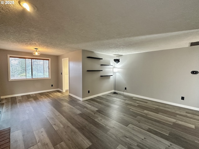 interior space featuring visible vents, a textured ceiling, baseboards, and dark wood-type flooring