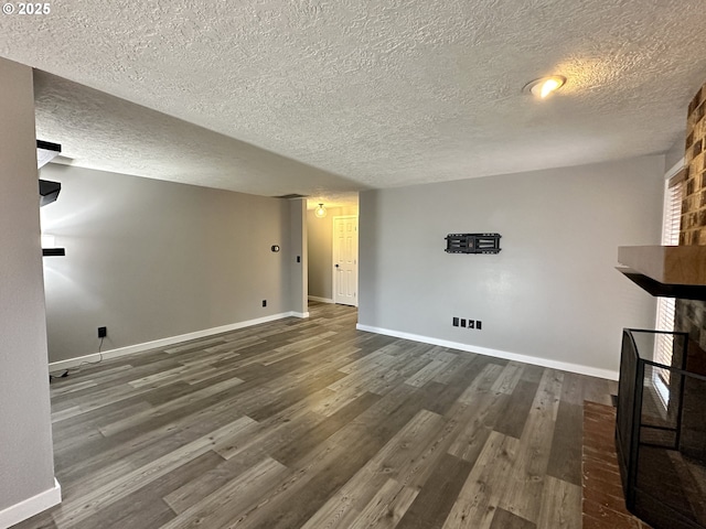 unfurnished living room featuring dark wood-style flooring, a fireplace, a textured ceiling, and baseboards