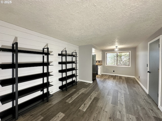 interior space with a textured ceiling, dark wood finished floors, and baseboards