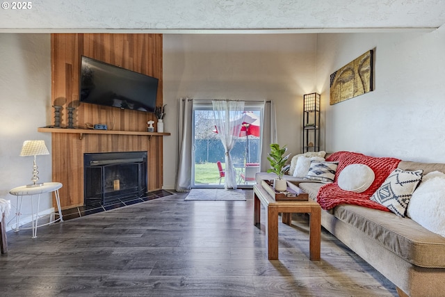 living room featuring a fireplace with flush hearth and dark wood finished floors