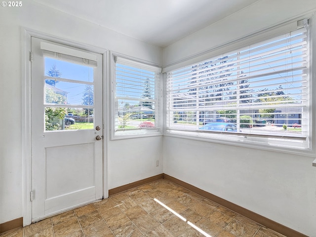 entryway featuring baseboards, stone finish flooring, and a wealth of natural light