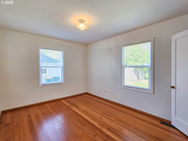 spare room featuring baseboards, visible vents, a wealth of natural light, and light wood finished floors