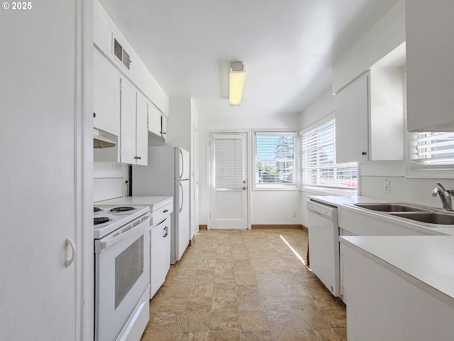kitchen with white appliances, white cabinetry, plenty of natural light, and a sink