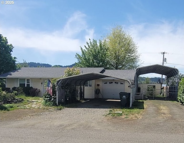 ranch-style house with dirt driveway, a carport, fence, and an attached garage