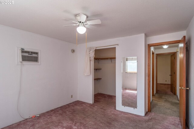 unfurnished bedroom featuring carpet flooring, a wall unit AC, a closet, and a ceiling fan