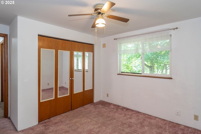 unfurnished bedroom with multiple windows, carpet, a ceiling fan, and a closet