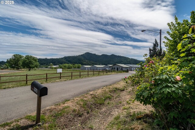 view of asphalt road featuring a mountain view and street lights