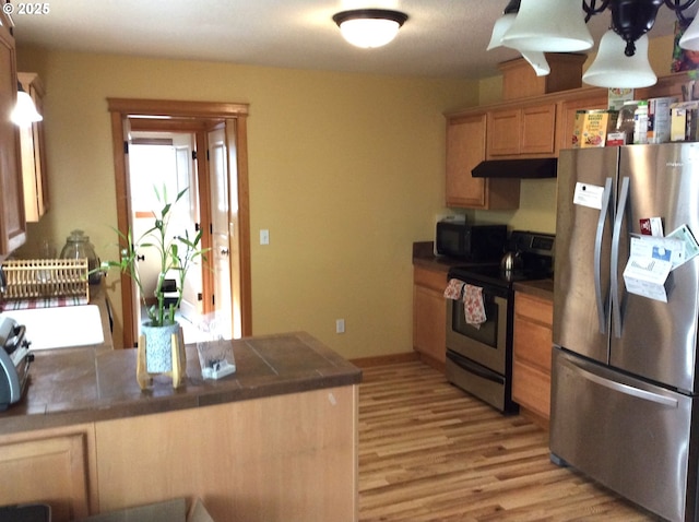 kitchen featuring appliances with stainless steel finishes, tile countertops, light hardwood / wood-style floors, and kitchen peninsula