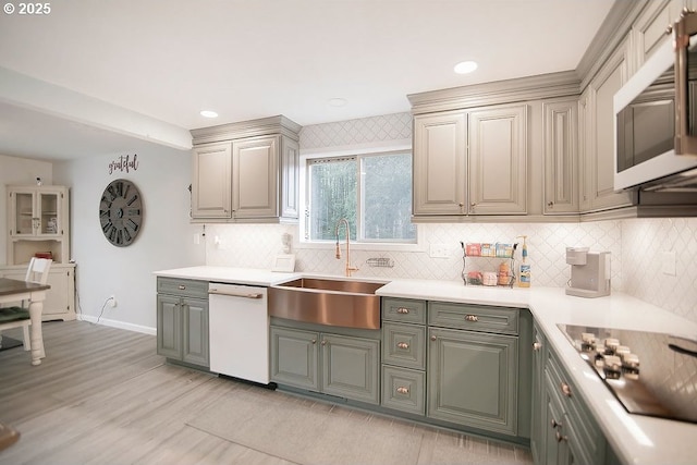 kitchen featuring light wood-style flooring, white appliances, a sink, decorative backsplash, and light countertops