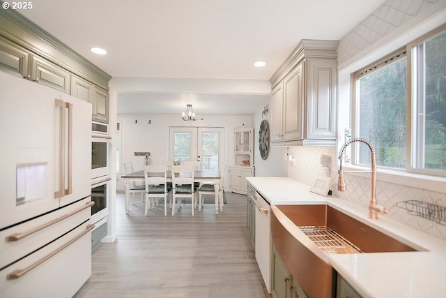 kitchen with light countertops, tasteful backsplash, a sink, and white appliances