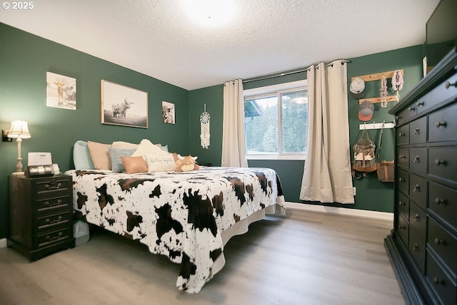 bedroom with a textured ceiling, wood finished floors, and baseboards