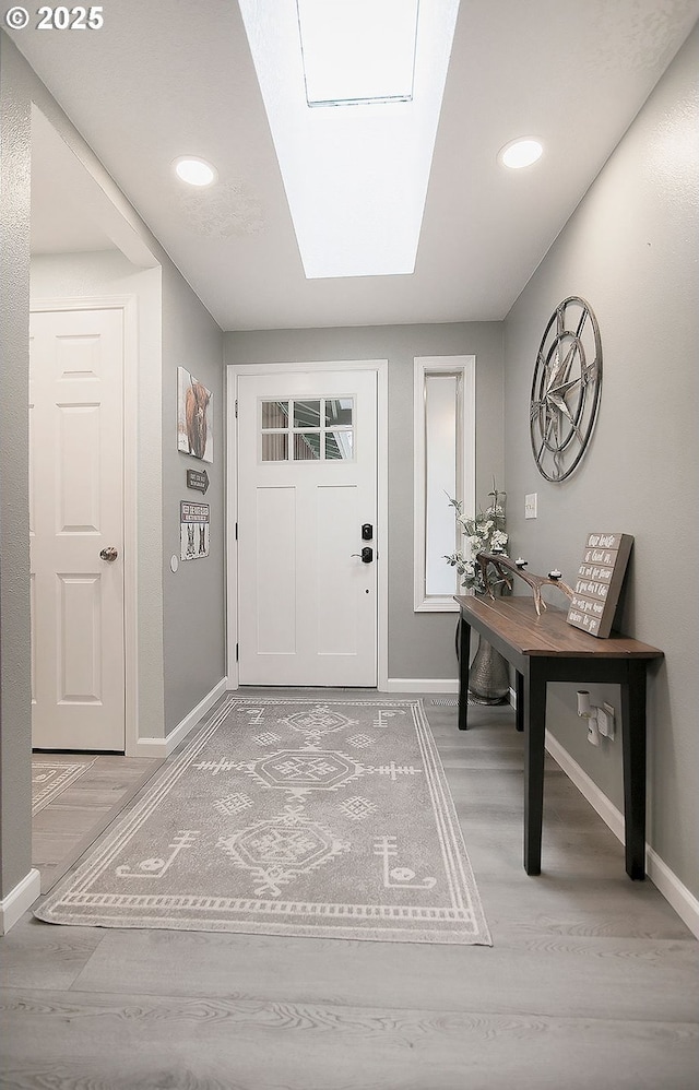 entrance foyer with light wood-style floors, baseboards, a skylight, and recessed lighting