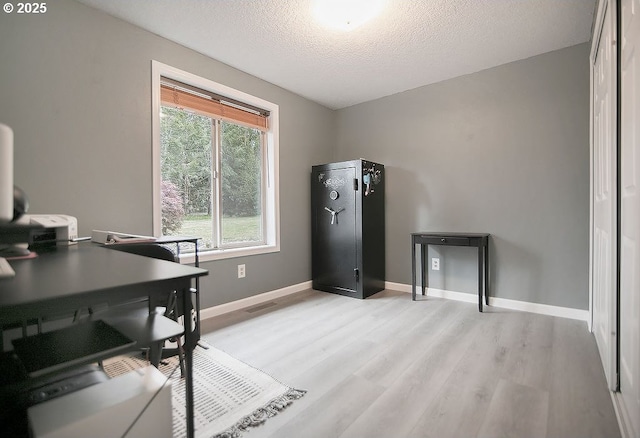 office area featuring light wood finished floors, a textured ceiling, baseboards, and visible vents