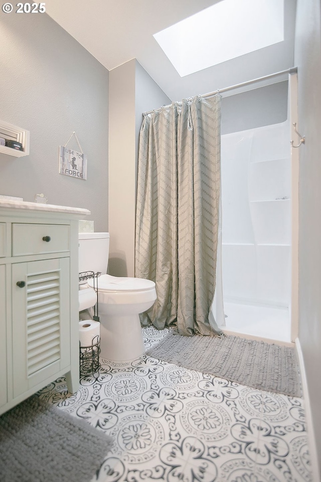 full bath featuring a stall shower, vanity, a skylight, and toilet