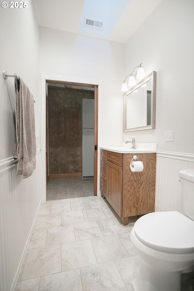 half bathroom with vanity, toilet, and visible vents
