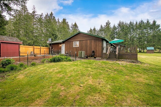 back of property featuring a yard, an outbuilding, a shed, central air condition unit, and a wooden deck