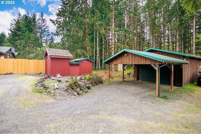 view of vehicle parking with fence, a storage unit, and a detached garage