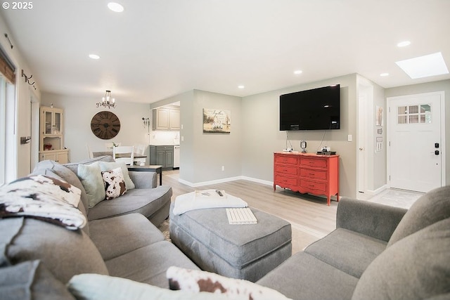 living area with light wood-style flooring, recessed lighting, baseboards, a chandelier, and a skylight