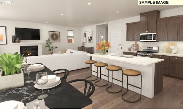 kitchen featuring a sink, open floor plan, stainless steel appliances, a breakfast bar area, and dark wood-style flooring