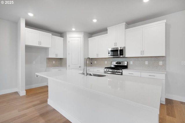 7864 NW Eleanor Ave, Portland, OR 97229 - kitchen with baseboards, appliances with stainless steel finishes, an island with sink, and a sink
