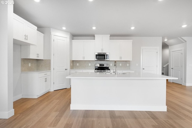 7864 NW Eleanor Ave, Portland, OR 97229 - kitchen featuring backsplash, stainless steel appliances, a kitchen island with sink, and a sink