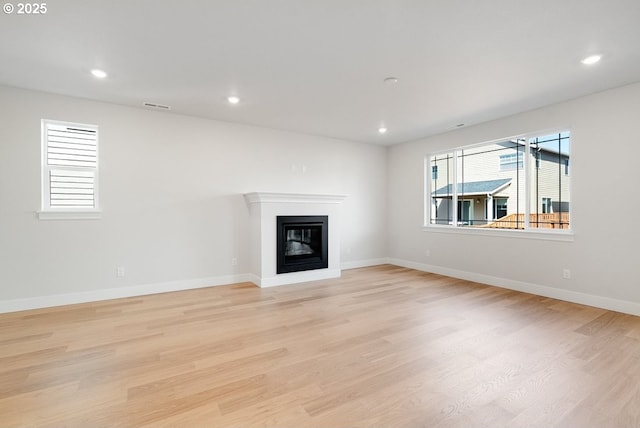 7864 NW Eleanor Ave, Portland, OR 97229 - unfurnished living room featuring recessed lighting, light wood finished floors, visible vents, baseboards, and a glass covered fireplace
