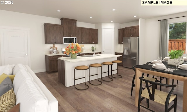 kitchen with wood finished floors, white microwave, stainless steel fridge with ice dispenser, a sink, and light countertops