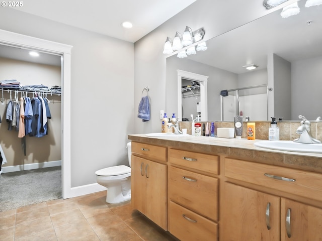 bathroom with tile patterned flooring, vanity, toilet, and walk in shower