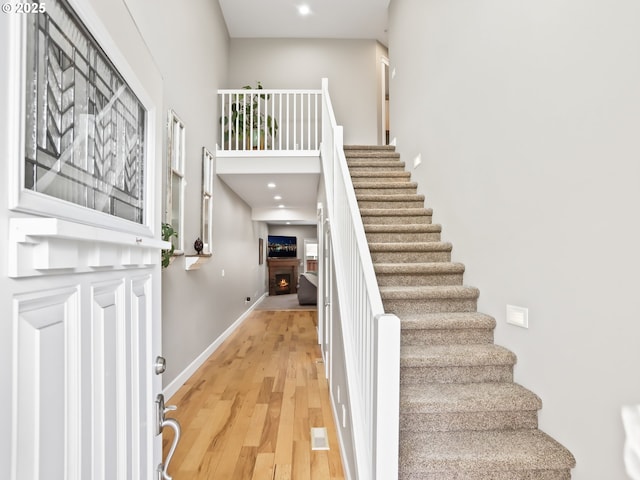 stairway featuring a towering ceiling and hardwood / wood-style floors