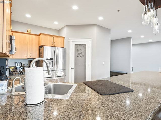 kitchen featuring appliances with stainless steel finishes, sink, light brown cabinets, and decorative light fixtures