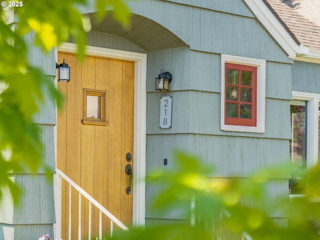 view of exterior entry with a shingled roof